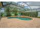 Inviting screened-in pool with a unique shape, featuring a small waterfall and surrounded by lush landscaping at 2146 Gold Dust Ct, Trinity, FL 34655