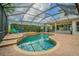 Inviting screened-in pool featuring a small waterfall and surrounded by lush landscaping and patio seating at 2146 Gold Dust Ct, Trinity, FL 34655