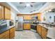 Well-lit kitchen boasts stainless steel appliances, wooden cabinetry, and stylish gray tile floors at 2507 Dewberry St, Valrico, FL 33596