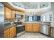Modern kitchen featuring stainless steel appliances, wooden cabinets, and seamless flow to living area at 2507 Dewberry St, Valrico, FL 33596