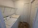 A compact laundry room with a washer, dryer, shelving, and a neutral tiled floor at 2614 Queen Alberta Dr, Valrico, FL 33594