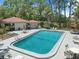 Community pool surrounded by lounge chairs and lush landscaping with a nearby clubhouse at 2650 Countryside Blvd # A210, Clearwater, FL 33761