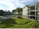 Condo exterior with balconies, well-maintained lawn, tropical palm tree, and partial water view at 2700 Bayshore Blvd # 5210, Dunedin, FL 34698