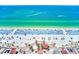 Stunning aerial view of a crowded beach with crystal-clear turquoise water, white sand, and rows of blue beach umbrellas at 301 S Gulfview Blvd # 301, Clearwater Beach, FL 33767