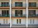 Rear exterior view with upper balconies and ground-level patios, enhanced by green railings at 320 Island Way # 205, Clearwater Beach, FL 33767
