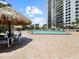 Large pool area with tables, chairs, and thatched umbrellas for shading at 320 Island Way # 205, Clearwater Beach, FL 33767