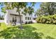 The backyard shows a plush lawn with a young tree offering shade near the modern white home at 3616 W Anderson Ave, Tampa, FL 33611