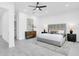 Spacious bedroom featuring a ceiling fan, a gray headboard with white bedding, and warm lamps on the bedside tables at 3616 W Anderson Ave, Tampa, FL 33611