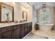 Bright bathroom featuring a double vanity, soaking tub under a large window, and neutral color palette at 4320 Auston Way, Palm Harbor, FL 34685