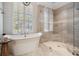 Elegant bathroom features a modern soaking tub, a glass shower, and a large window with shutters at 4320 Auston Way, Palm Harbor, FL 34685