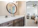 Well-lit bathroom with a wood vanity, a modern mirror, and a glimpse into an adjacent bedroom at 4320 Auston Way, Palm Harbor, FL 34685