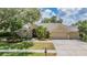 Charming home featuring a three car garage, a well-manicured lawn and lush tropical landscaping at 4320 Auston Way, Palm Harbor, FL 34685