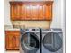 Functional laundry room with modern washer and dryer, granite countertop, and upper cabinets at 4320 Auston Way, Palm Harbor, FL 34685
