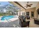 Covered lanai with wicker seating area overlooks the pool and surrounding landscape at 4320 Auston Way, Palm Harbor, FL 34685