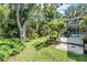 Beautiful backyard with lush landscaping, view of deck and pool enclosure in the background at 4797 Stonebriar Dr, Oldsmar, FL 34677