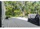 Backyard deck with outdoor shower, grill and surrounding plants and trees at 4797 Stonebriar Dr, Oldsmar, FL 34677