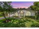 Charming home featuring a well-manicured lawn, arched windows, and a blue front door at sunset at 4797 Stonebriar Dr, Oldsmar, FL 34677