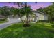 Charming single-story home with well-manicured lawn and lush palm trees and a vibrant blue front door at 4797 Stonebriar Dr, Oldsmar, FL 34677