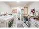 Bright laundry room with stainless steel sink, front-load washer and dryer, and black and white tiled floor at 4797 Stonebriar Dr, Oldsmar, FL 34677