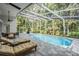 Backyard screened-in pool with lounge chairs, dining area, ceiling fans and surrounding green trees at 4797 Stonebriar Dr, Oldsmar, FL 34677
