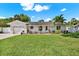 Charming white brick home featuring a lush green lawn, beautiful landscaping, and a welcoming front entrance at 5008 Stolls Ave, Tampa, FL 33615