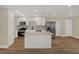 Kitchen boasts white cabinetry, stainless steel appliances, island with a quartz countertop, and wood flooring at 5008 Stolls Ave, Tampa, FL 33615