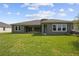 Spacious backyard featuring a well-maintained lawn and the home's exterior with multiple windows and doors at 5116 Wildwind Dr, Apollo Beach, FL 33572