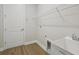 Well-lit laundry room featuring wood-look flooring, storage shelf, sink and white painted trim at 5116 Wildwind Dr, Apollo Beach, FL 33572