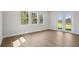 Bright room with light wood floors, three windows, and glass patio doors leading to outdoors at 5116 Wildwind Dr, Apollo Beach, FL 33572