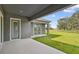 View of the home's outdoor living space with a covered patio, green lawn, and lush landscaping at 5116 Wildwind Dr, Apollo Beach, FL 33572
