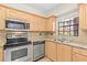 Modern kitchen features stainless steel appliances, tile backsplash, wood cabinets and large window at 6100 Gulfport S Blvd # 114, Gulfport, FL 33707