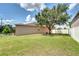 A spacious backyard features a large tree, manicured lawn, and a fence, creating a private outdoor oasis at 6519 Twin Bridges Dr, Zephyrhills, FL 33541