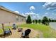 A cozy backyard with a fire pit and chairs overlooks a serene pond, perfect for relaxing and entertaining at 6519 Twin Bridges Dr, Zephyrhills, FL 33541