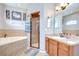 Bright bathroom featuring double vanities, a soaking tub with tile surround and a separate shower with a glass door at 6519 Twin Bridges Dr, Zephyrhills, FL 33541