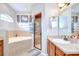 Bright bathroom featuring double vanities, a soaking tub with tile surround and a separate shower with a glass door at 6519 Twin Bridges Dr, Zephyrhills, FL 33541