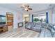 Bright living room with hardwood floors, a ceiling fan, sectional couch, and view to the backyard at 6519 Twin Bridges Dr, Zephyrhills, FL 33541