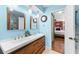 Stylish bathroom boasting a dual sink vanity with wood drawers, elegant lighting, and an open doorway to the bedroom at 8315 W Elm St, Tampa, FL 33615