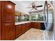 Traditional kitchen with wood cabinets, tile floor, black dishwasher, and a window overlooking backyard at 8315 W Elm St, Tampa, FL 33615