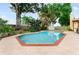 In-ground pool with a brick-lined border and a fenced perimeter with mature trees at 8315 W Elm St, Tampa, FL 33615