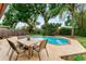 Outdoor pool surrounded by lush green landscaping with a patio dining area at 8315 W Elm St, Tampa, FL 33615