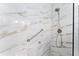 Tiled shower featuring marble look tiles, a shower head and an assist bar for safety and convenience at 8315 W Elm St, Tampa, FL 33615