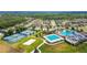 An aerial view of a community featuring swimming pools, tennis courts, and well-maintained homes amid green spaces at 8413 Swiss Chard Cir, Land O Lakes, FL 34637