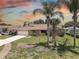 Charming home with brick accents, landscaped lawn and swaying palm trees against a colorful sky at 8521 Caitlin Ct, Hudson, FL 34667