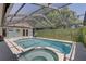Sparkling pool and spa area surrounded by a screened enclosure and lush greenery at 8521 Caitlin Ct, Hudson, FL 34667