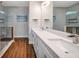 Bathroom featuring double vanity, quartz countertops, framed mirrors, and glass shower at 8608 N Arden Ave, Tampa, FL 33604