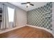 Modern bedroom with wood-look floors, a leaf-patterned accent wall, and ample natural light at 8608 N Arden Ave, Tampa, FL 33604