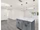 Gray kitchen island with white quartz countertop and storage cabinets; modern lighting fixture at 9266 Century Dr, Spring Hill, FL 34606