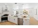 Bright kitchen features white cabinets, stainless steel appliances, and hardwood floors at 970 Ridgewood Ter, Tarpon Springs, FL 34689