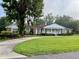 Classic brick home with a covered porch, well-maintained lawn, and a circular driveway on a foggy morning at 1002 W Pinedale Dr, Plant City, FL 33563