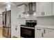 Modern kitchen featuring white cabinets, stainless steel appliances, and a stainless steel range hood at 10744 Drummond Rd, Tampa, FL 33615